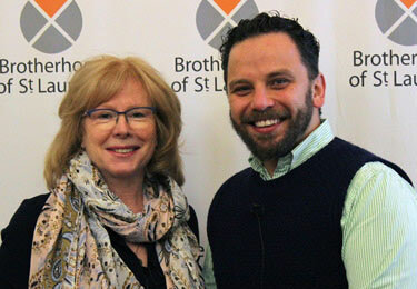 Woman and man standing in front of a Brotherhood of St Laurence banner