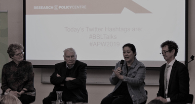 Four people site on a panel at an event