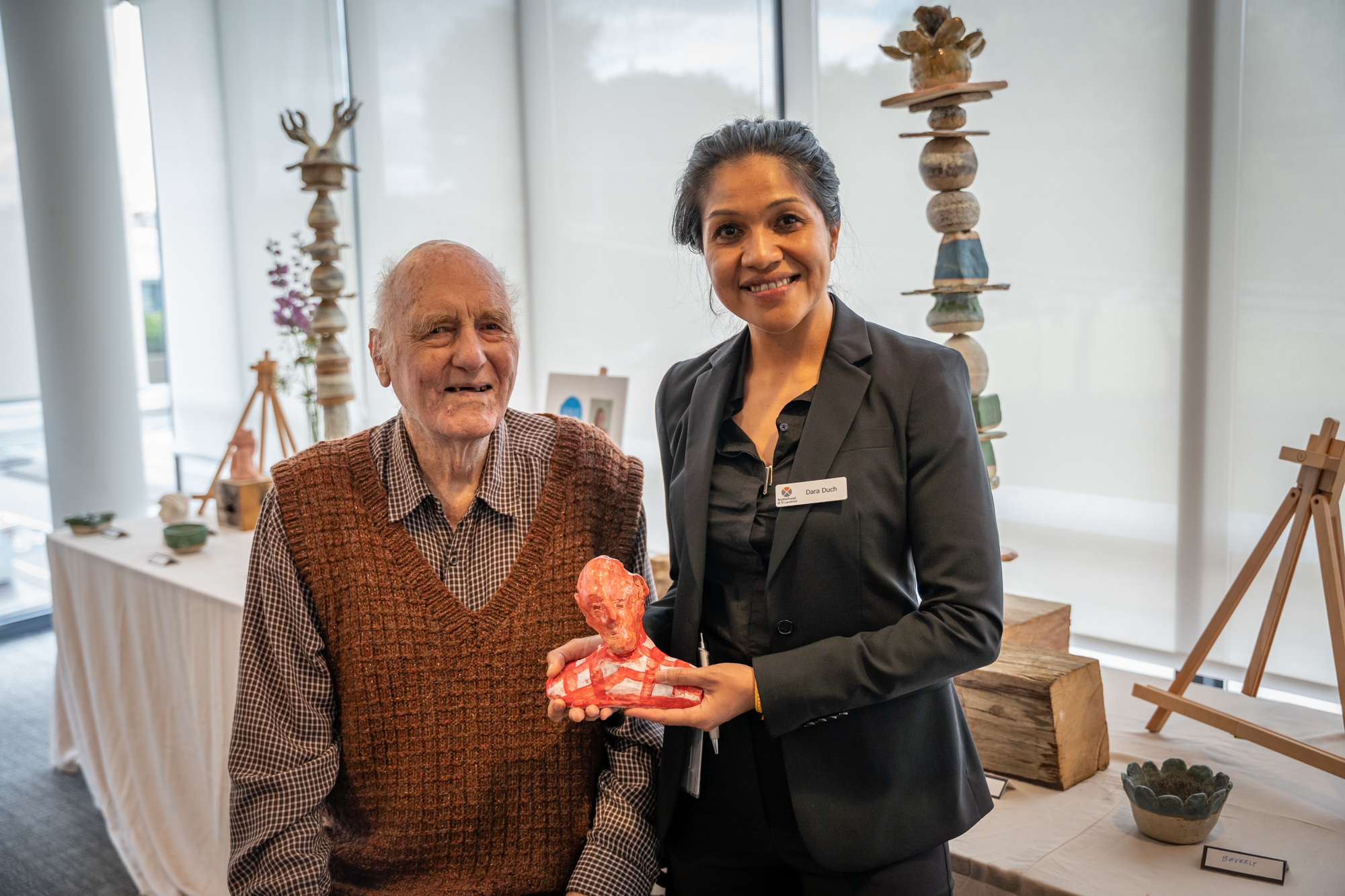 Resident and artist Noel Belfrage with staff member Dara Duch who is holding the clay sculpture he created.