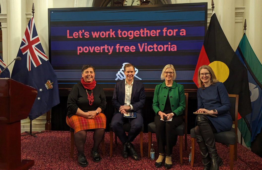 The Partnering for a poverty-free Victoria panel hosted by Hutch Hussein speaking with left to right: BSL’s Executive Director Travers McLeod, (VCOSS) CEO, Emma King and CEO of the Grattan Institute, Danielle Wood. They are seated in front of a screen with the words ‘Let’s work together for a poverty free Victoria’ on it and on either side of them are the Australia and First Nations flags