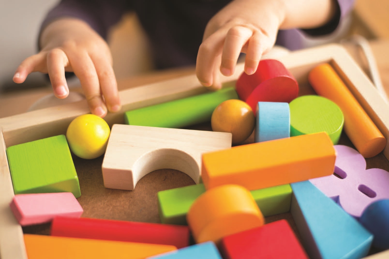 toddlers hands playing wooden blocks