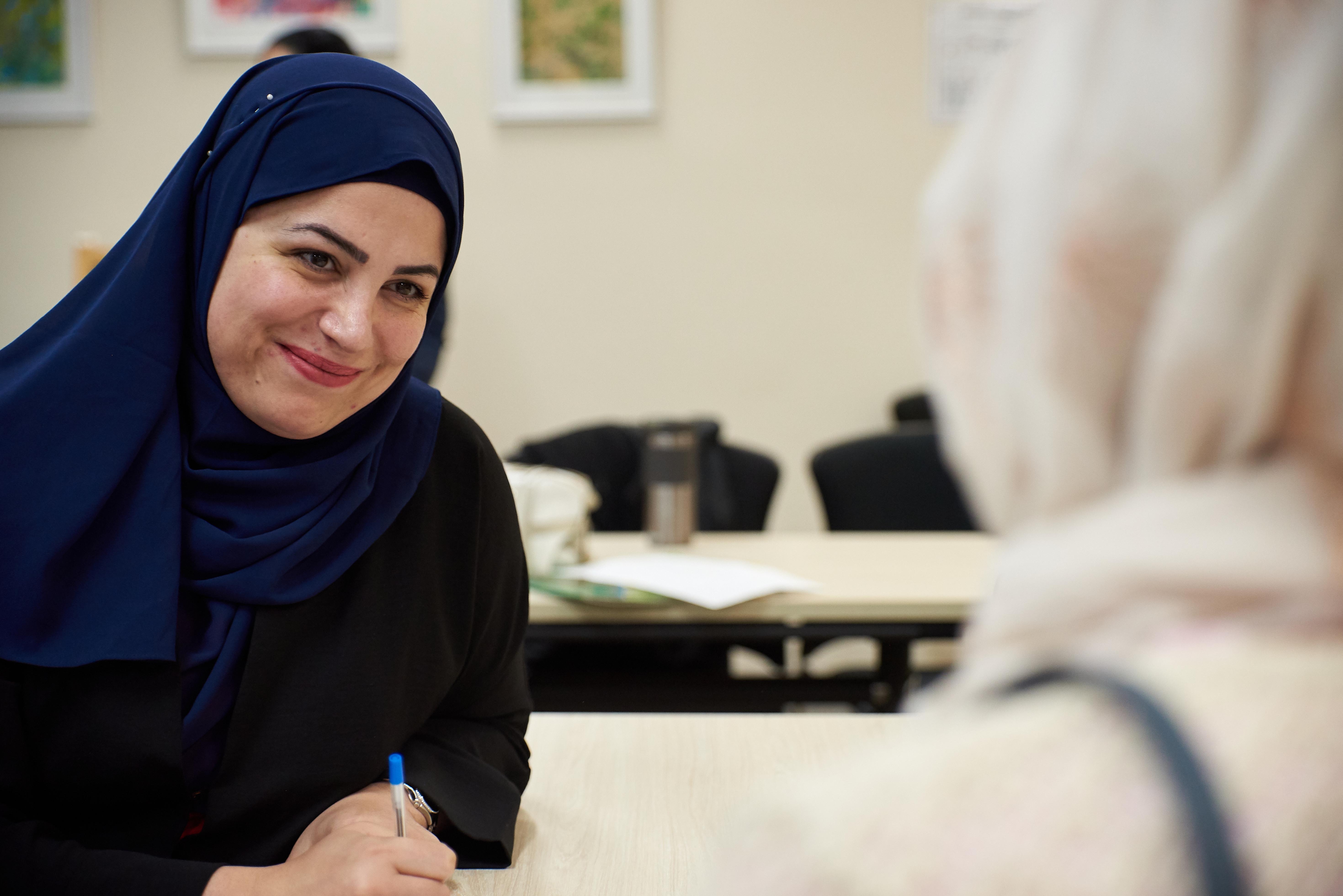 A smiling woman interviewing another woman