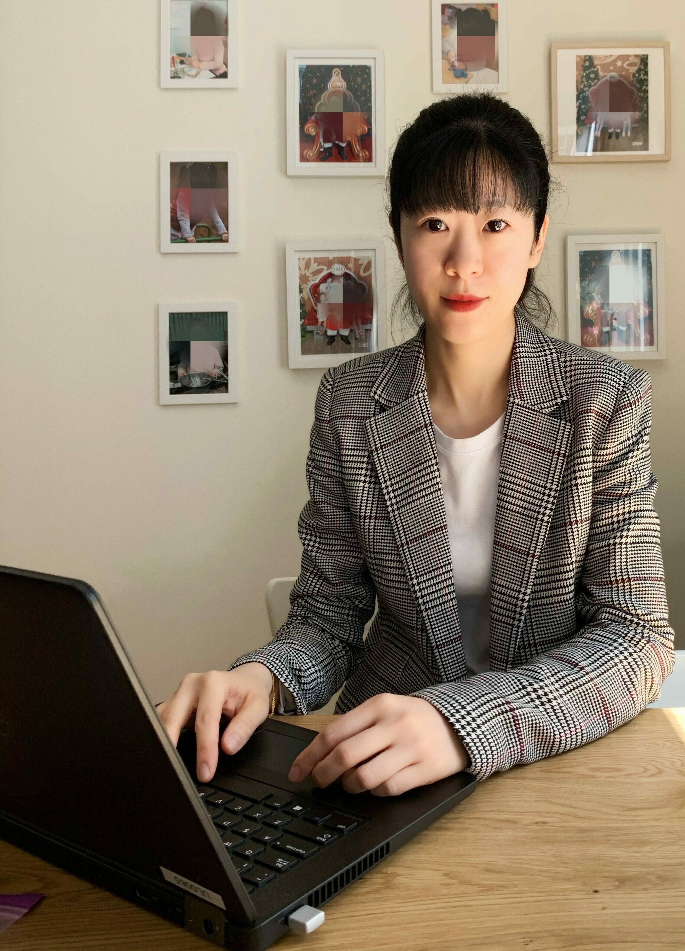 A woman in corporate clothes sits at a desk with a laptop