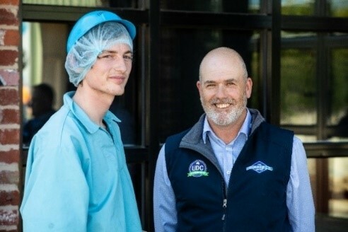 A young man in food hygiene safety clothes stands with a man