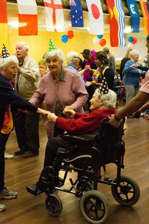 Older woman in wheelchair dancing with friends