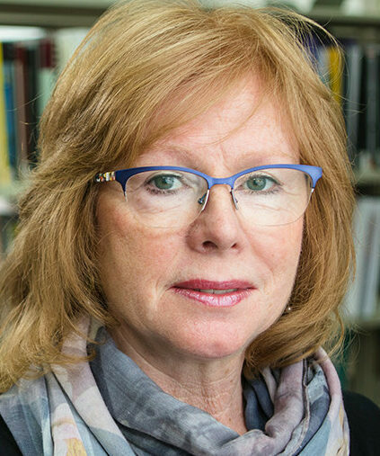 A woman standing in front of shelves of books looking at the camera