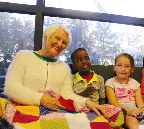 Colourful blanket over knees of volunteer and two children