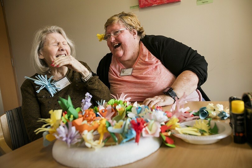 Paper flowers, staff and participant laughing