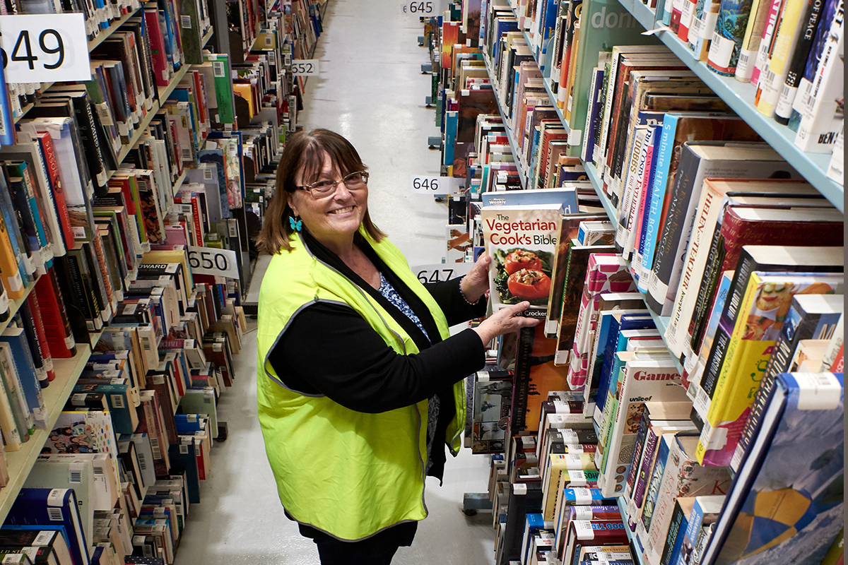 A woman stands amongst rows of shelves