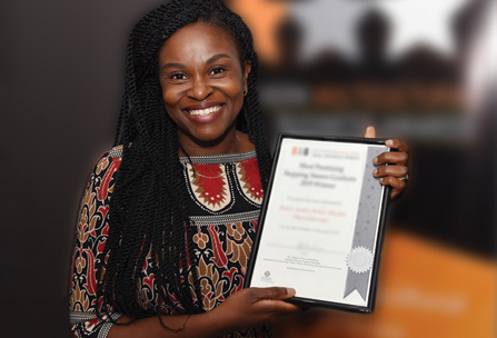A woman smiles and holds a framed certificate