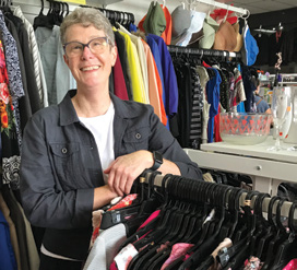 A woman stands beside clothing racks in a store