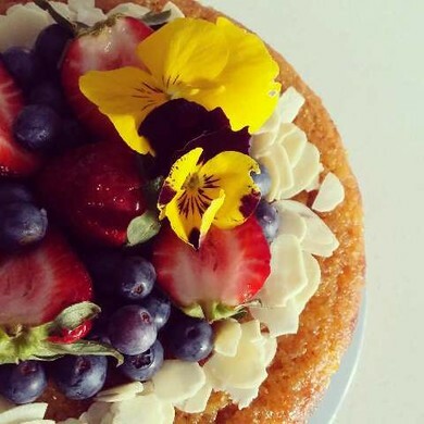 Cake decorated with shaved almonds, berries and flowers